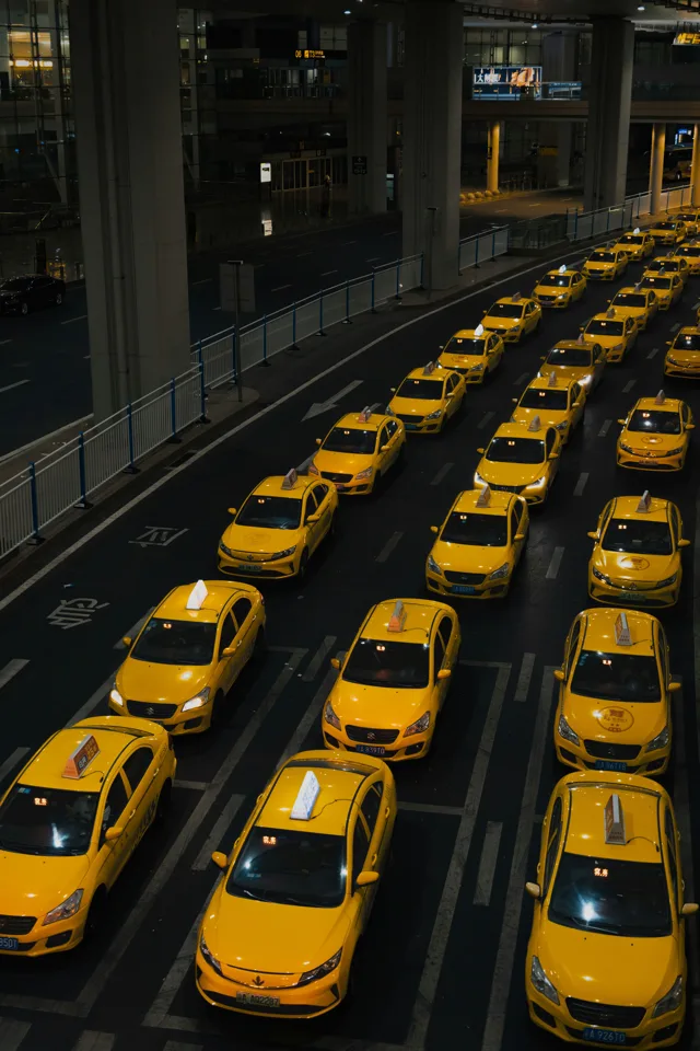 A fleet of taxis lined up outside a Chinese airport terminal