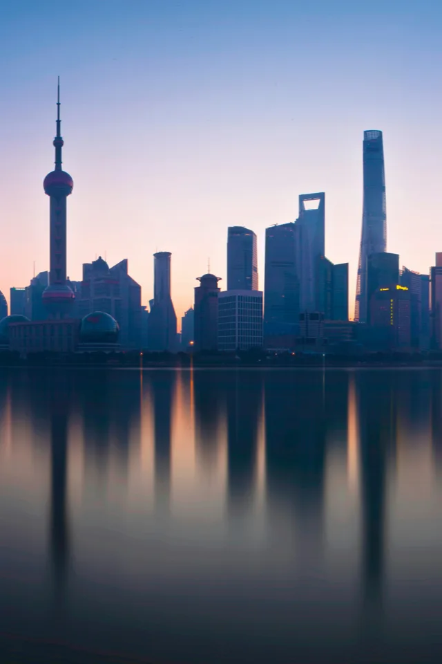 A modern Chinese city skyline at night with light trails from traffic