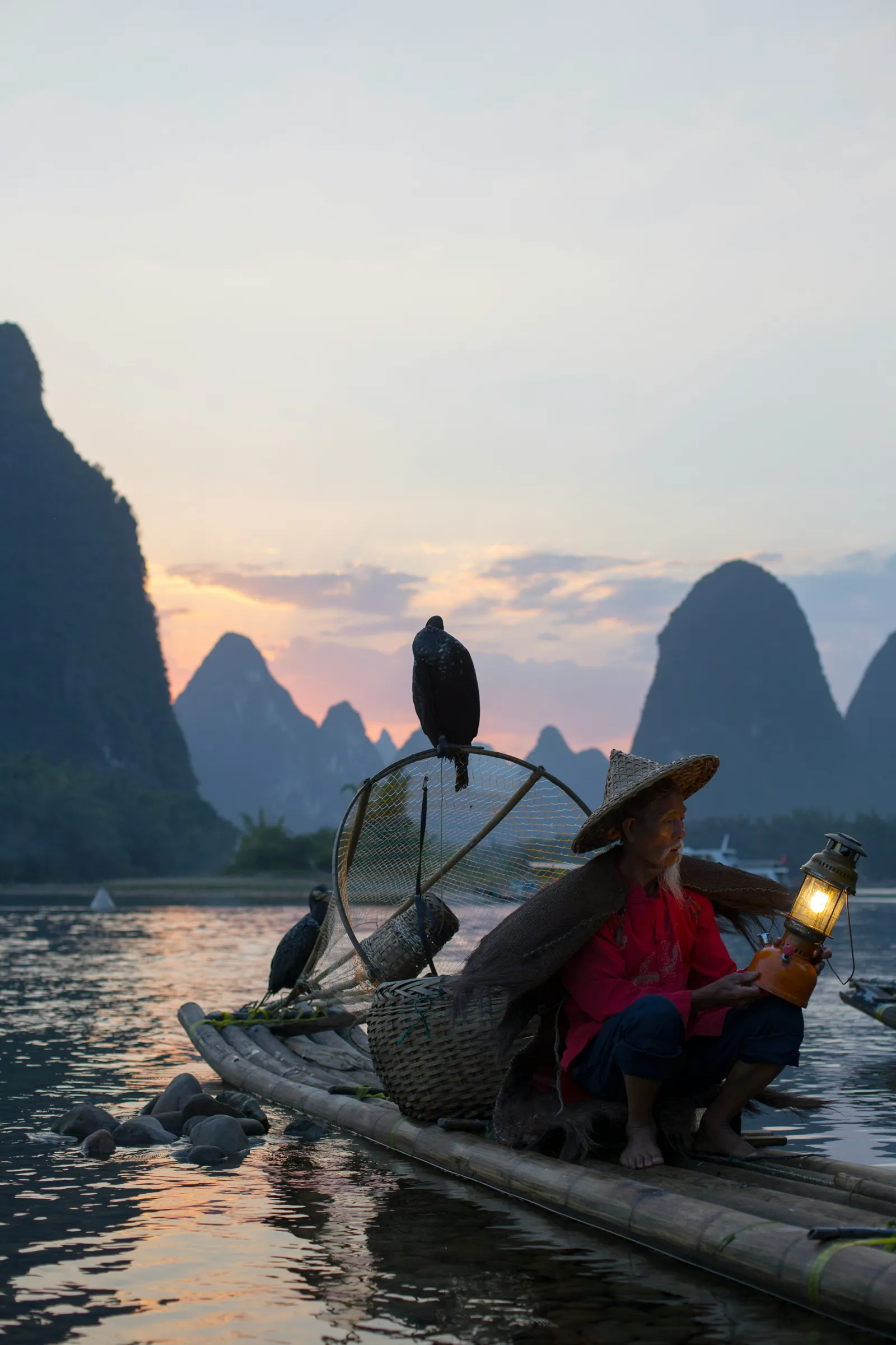 A bamboo raft on the still Li River below misty karst peaks near Yangshuo