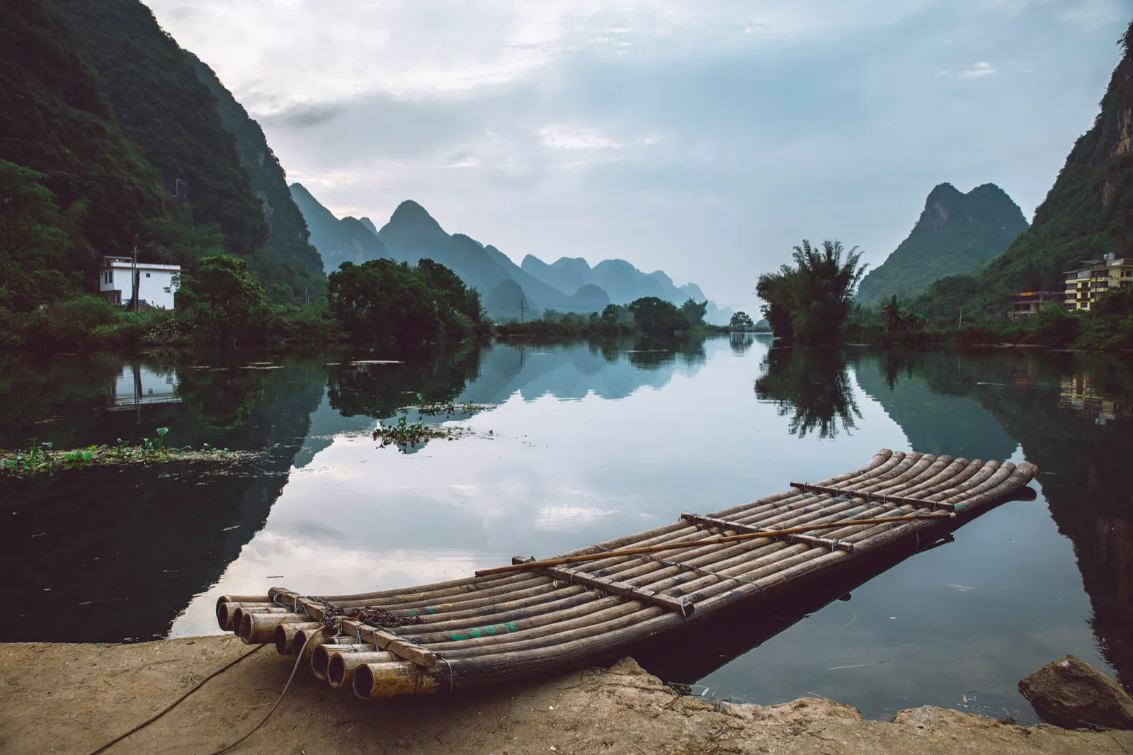 A bamboo raft on a mirror-still river reflecting karst peaks in Guilin