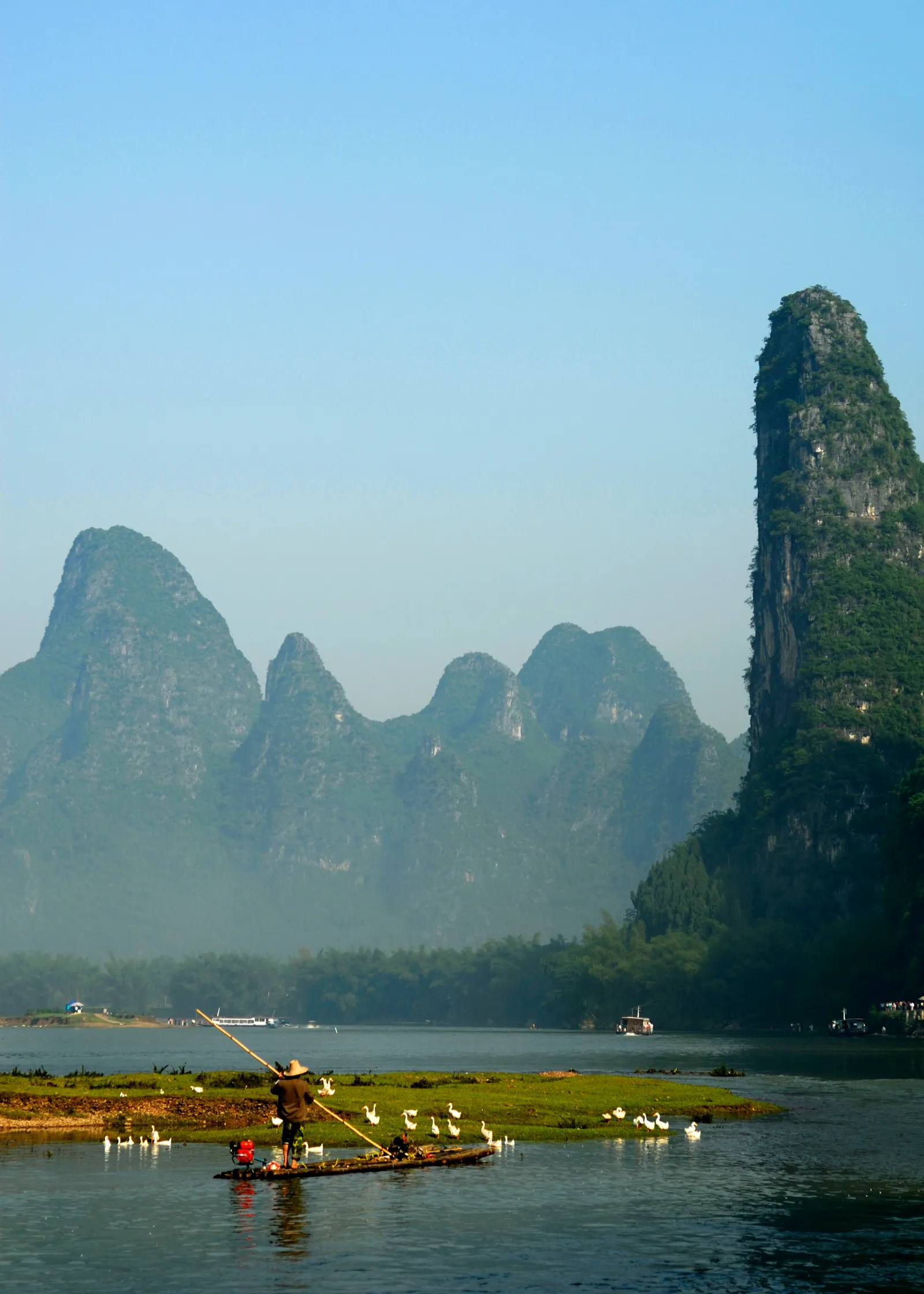A fisherman on a bamboo raft on the Li River at dusk