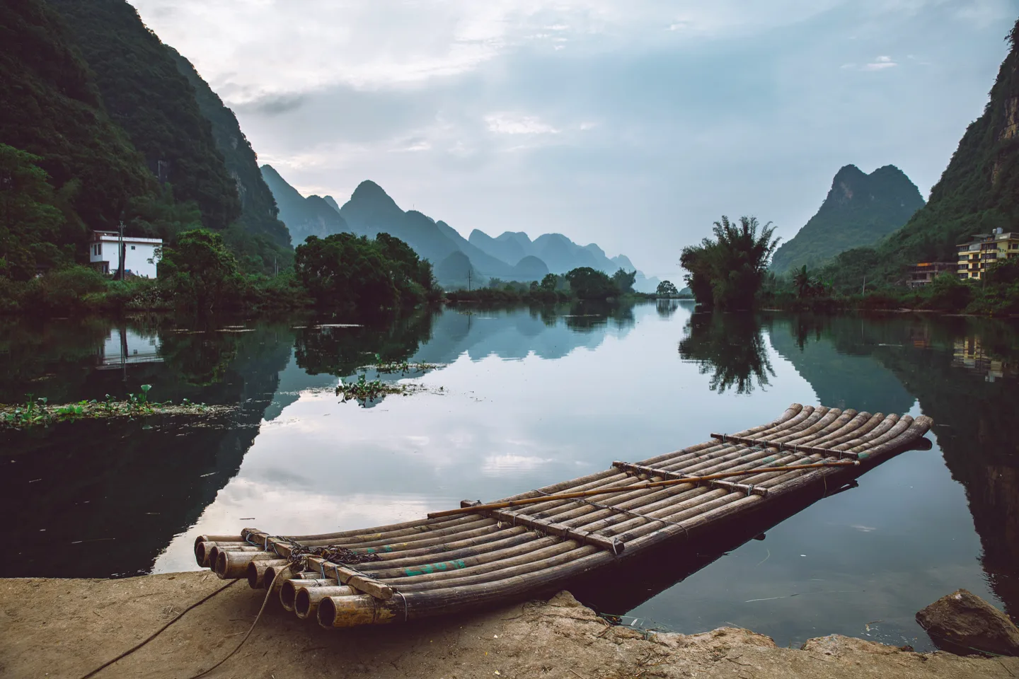 A bamboo raft on the still Li River below misty karst peaks near Yangshuo